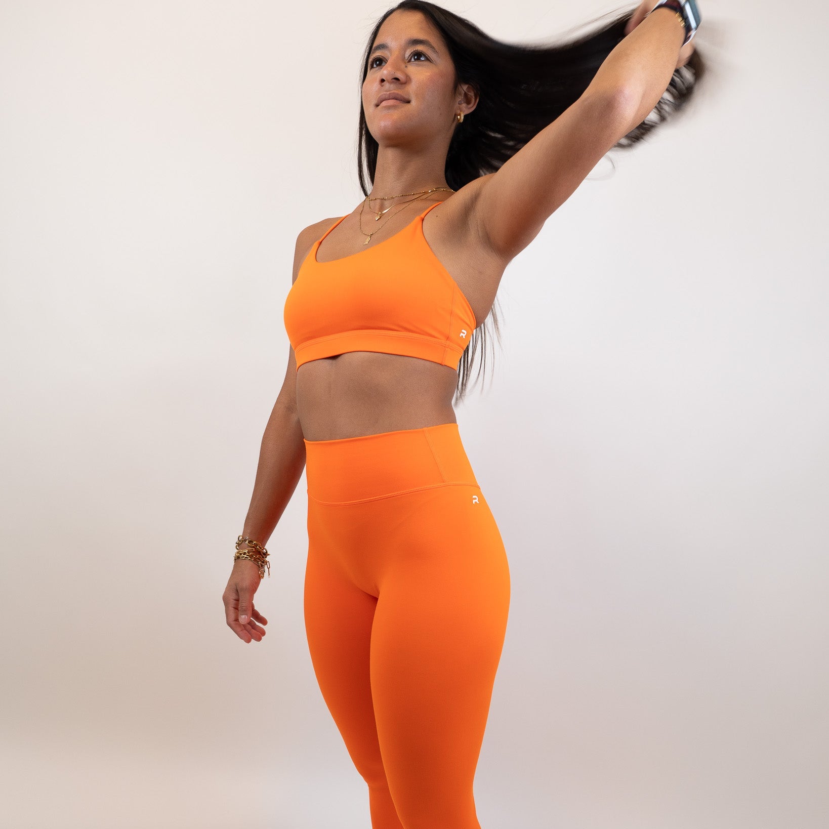 Woman wearing an orange athletic outfit on a white background